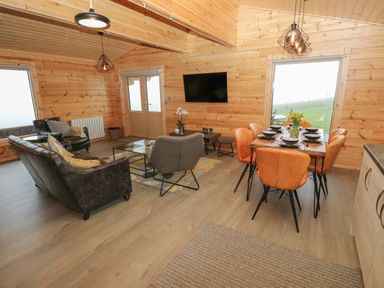 A living area with a sofa set and a dining table with six chairs at Height End Farm Log Cabin Rossendale near Bacup