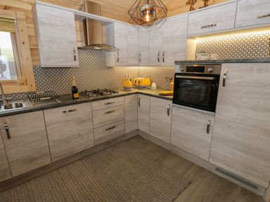 A kitchen with wooden cabinets black countertops yellow toaster and kettle and an oven at Height End Farm Log Cabin Rossendale near Bacup