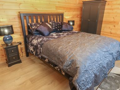 A bedroom with a double bed beside two bedside tables and a wardrobe at Height End Farm Log Cabin Rossendale near Bacup