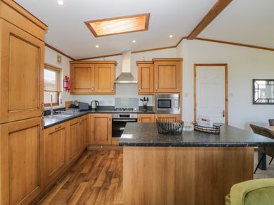 A kitchen with wooden cabinets a countertop island and appliances at Three Views Lodge in Whitsand Bay Fort Holiday Village