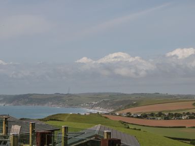 A coastal landscape with green fields and hills overlooking the sea at Three Views Lodge in Whitsand Bay Fort Holiday Village