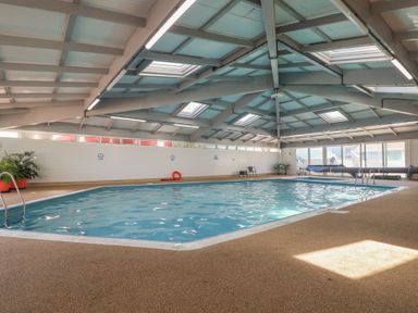 An indoor pool with seating and plants at Three Views Lodge in Whitsand Bay Fort Holiday Village