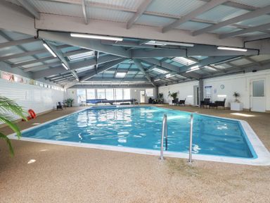 An indoor pool with a pool ladder and seating area at Three Views Lodge Whitsand Bay Fort Holiday Village