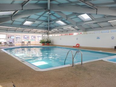 An indoor pool area with a swimming pool and seating at Three Views Lodge Whitsand Bay Fort Holiday Village