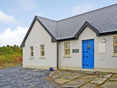 A house with a blue door and stone path in a rural setting at Bluebell Cottage in Spanish Point County Clare