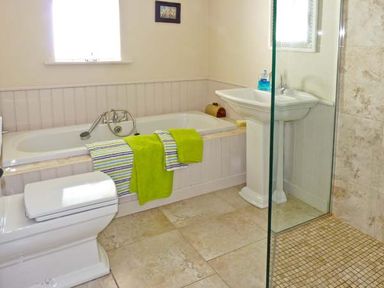 A bathroom with a bathtub towels toilet sink and glass shower area at Bluebell Cottage in Spanish Point County Clare