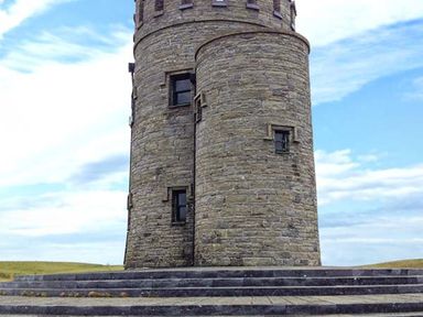 A stone tower with small windows on a stepped base under a blue sky