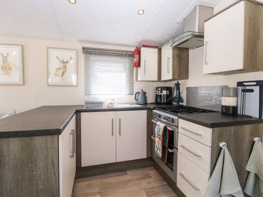 A kitchen with stove oven sink cabinets and wall art at Hazell Thorne Hideaway in Fritton