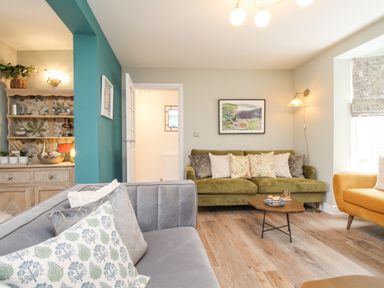 A living room with sofas cushions coffee table and a cabinet at Bay Cottage in Weymouth