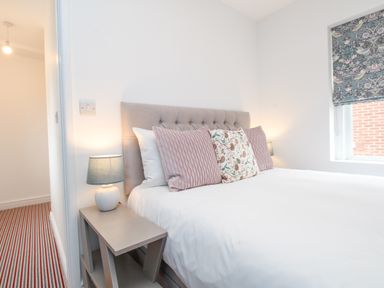 A bedroom with a bed with decorative pillows and bedside tables with lamps at Bay Cottage in Weymouth