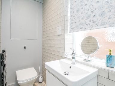 A bathroom with a toilet sink mirror and soap dispenser at Bay Cottage in Weymouth