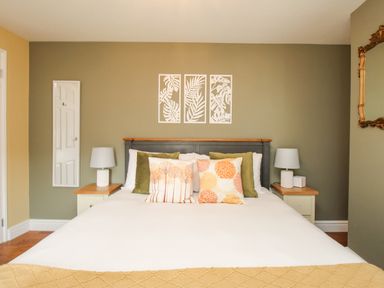 A bedroom with a bed with pillows bedside tables lamps and wall art at Bay Cottage in Weymouth