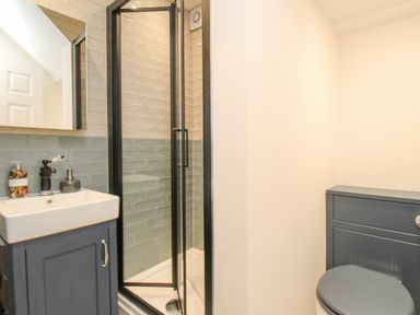 A bathroom with a shower enclosure sink with cabinet and toilet at Bay Cottage in Weymouth