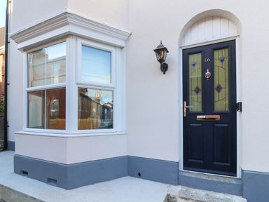 Front door with house number 16 and adjacent bay window of a house at Bay Cottage in Weymouth