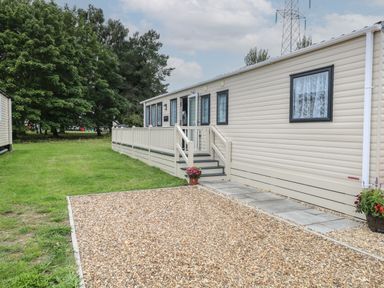 A caravan with stairs and a railing beside a gravel and grass area at Stanley's Lodge Foxburrow Hang in Belton Norfolk