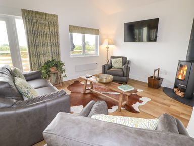 A living room with leather sofas a wooden coffee table and a wood-burning stove at Heritage Retreat in Monknash