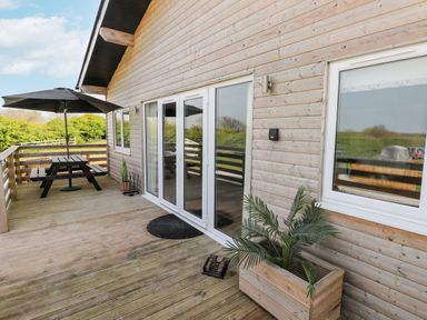 An outdoor deck with a table and umbrella at Heritage Retreat in Monknash