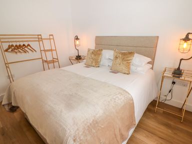 A bedroom with a bed with pillows and blankets and bedside tables with lamps at Monks Rest in Monknash