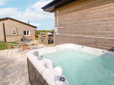 An outdoor area with a hot tub and seating at Monks Rest in Monknash