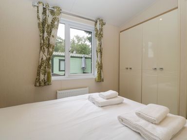 A bedroom with a bed and folded towels on it with a window and wardrobe at Dove in Shobdon