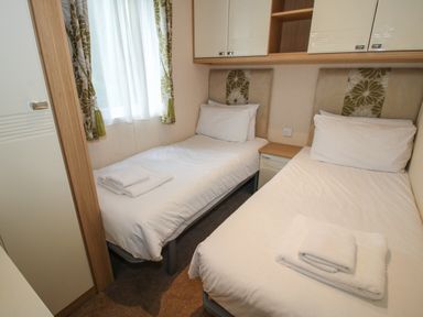 A small bedroom with two single beds and folded towels at Dove in Shobdon