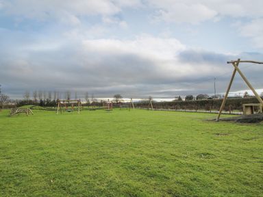 A playground with swings and a zip line on a grassy field at Dove in Shobdon