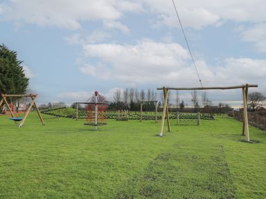 An outdoor playground with swings and climbing equipment on grass at Dove in Shobdon