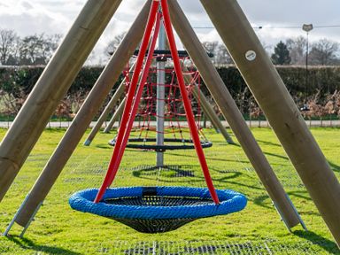 A swing and climbing frame in an outdoor play area at Dove in Shobdon