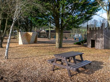 An outdoor playground with a picnic table, climbing wall, and playhouse at Dove, Shobdon