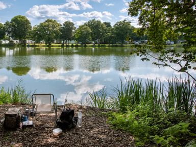 A lakeside scene with a chair, backpack, fishing rod, and water bottle at Dove in Shobdon