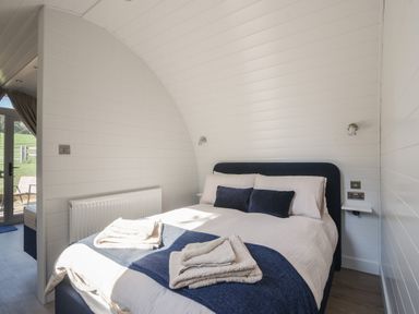A bedroom with a double bed with white and blue bedding and towels placed on top at Cedar in Wootton Fitzpaine near Charmouth