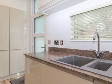 A kitchen with a marble countertop double sink and window with blinds at Serendipity R11 Fallbarrow Park near Bowness-On-Windermere