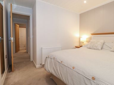 A bedroom with a bed lamp and doors leading to a hallway at Serendipity R11 Fallbarrow Park near Bowness-On-Windermere