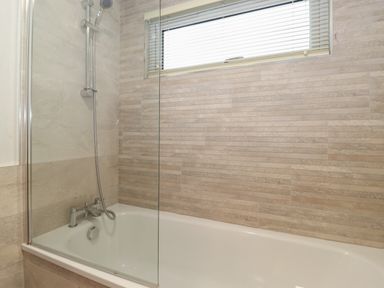 A bathroom with a bathtub shower and tiled walls with a window at Serendipity in R11 Fallbarrow Park near Bowness-On-Windermere