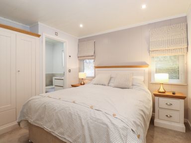 A bedroom with a double bed two bedside tables with lamps a wardrobe and windows with blinds at Serendipity R11 Fallbarrow Park near Bowness-On-Windermere