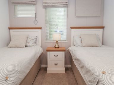 A bedroom with two single beds separated by a nightstand with a lamp at Serendipity R11 Fallbarrow Park near Bowness-On-Windermere