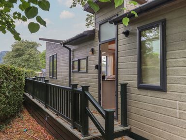 Exterior view of a modern house with open door and black railing at Serendipity R11 Fallbarrow Park near Bowness-On-Windermere