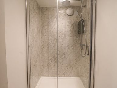 A shower cubicle with glass doors and a wall-mounted showerhead at The Woodpecker in Scarborough