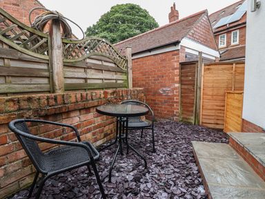 A small outdoor patio with two black chairs and a round glass table on stone chips at The Woodpecker in Scarborough