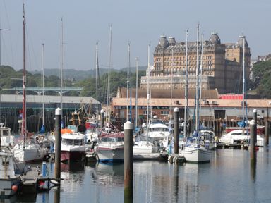 A marina with boats docked and a large building in the background at The Woodpecker in Scarborough