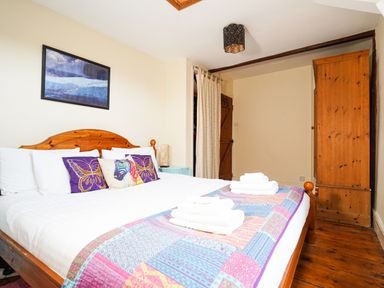 A bedroom with a wooden bed frame decorated with pillows and folded towels at Delfryn Goginan