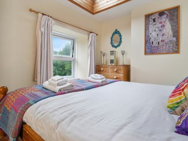 A bedroom with a bed with folded towels a wooden dresser and a window at Delfryn Goginan in Goginan near Aberystwyth