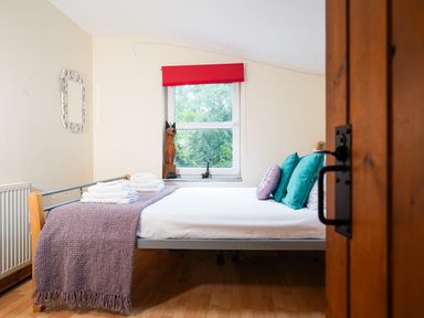 A bedroom with a bed with pillows and towels near a window with a red blind at Delfryn Goginan in Goginan near Aberystwyth
