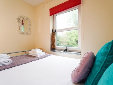 A bedroom with a bed pillows towels a window with cat figurines and a wall mirror at Delfryn Goginan Goginan near Aberystwyth