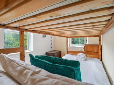 A bedroom with a wooden bunk bed a chest of drawers and a wooden chest by windows at Delfryn Goginan in Goginan near Aberystwyth