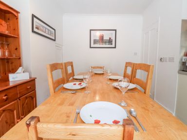 A dining room with a wooden table set with plates glasses and cutlery and wooden chairs at The Pink House in Felixstowe Suffolk