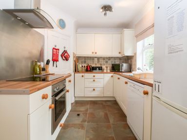 A kitchen with white cabinets wooden countertops and tiled floor at The Pink House in Felixstowe Suffolk