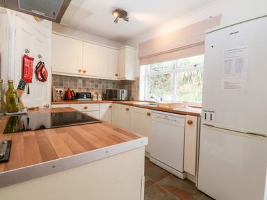 A kitchen with white cabinets wooden countertops a stove a dishwasher a refrigerator and a window at The Pink House in Felixstowe Suffolk