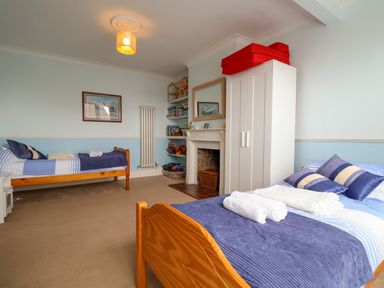 A bedroom with two single beds blue bedding a white wardrobe and a fireplace at The Pink House in Felixstowe Suffolk