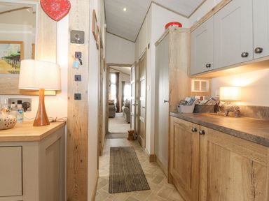 A hallway with wooden cabinets and a lamp at Pine Lake View in Coniston View 3 Carnforth